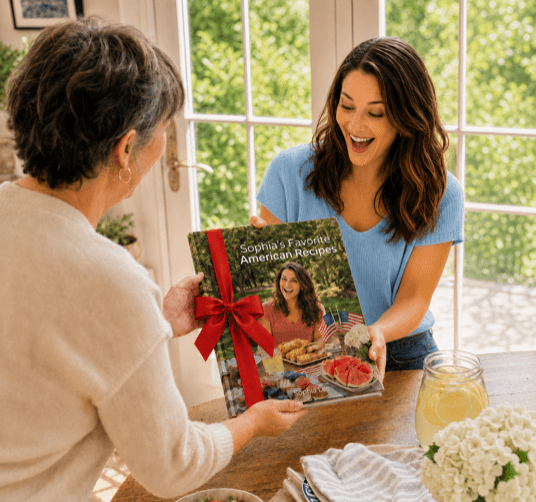 A woman handing over a personalized cookbook wrapped with a red bow